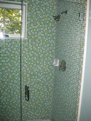 Green mosaic style tiled shower with a small window