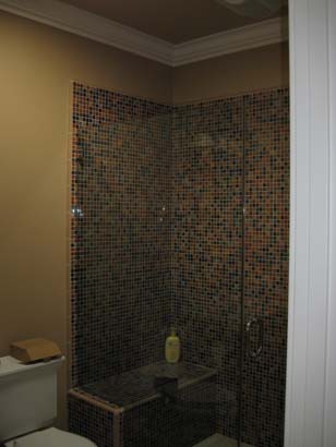 Multi-colored mosaic style shower with black, green, yellow, and orange tiles