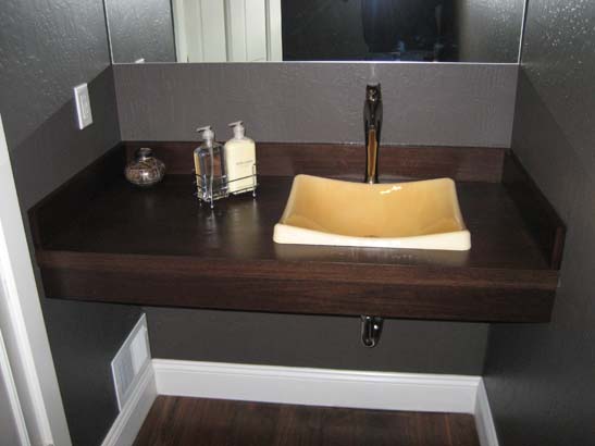 Ceramic bowl shaped sink with a stainless steel faucet on a polished dark standalone counter