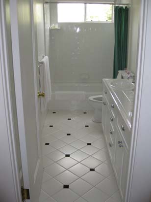White tile with small black tile patterned bathroom, with white cabinetry