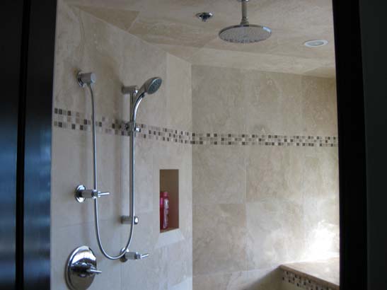 Stainless steel shower fixtures in a tan tiled shower