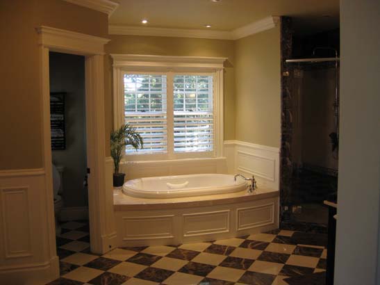 Bath tub next to a double window in a brown and tan checkered tile pattern bathroom.