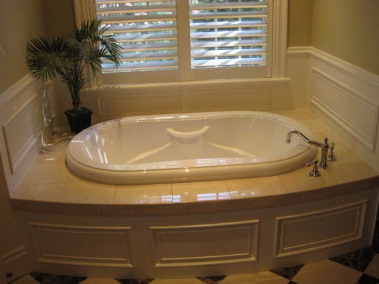 Inset bath tub below a double window with vintage fixtures