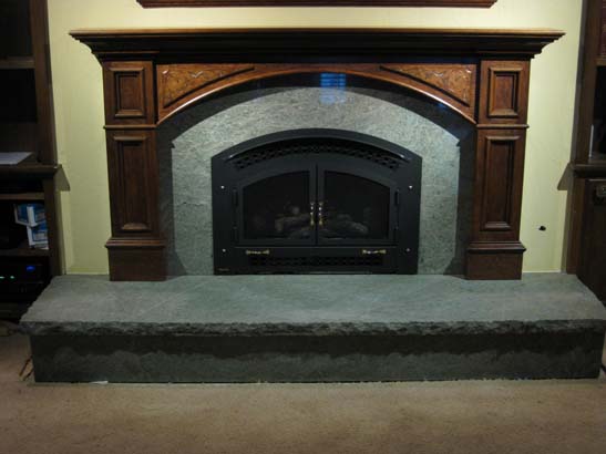 Close up after shot of a cherrywood paneled gas fireplace with green marbel mantel.